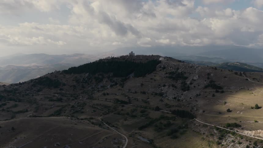 Slow aerial dolly shot reveals the ancient Rocca Calascio castle on a mountain peak in the Italian countryside