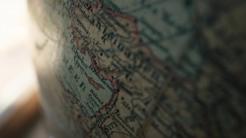 A cinematic close-up of a vintage globe with a slow focus pull over an old map of the world