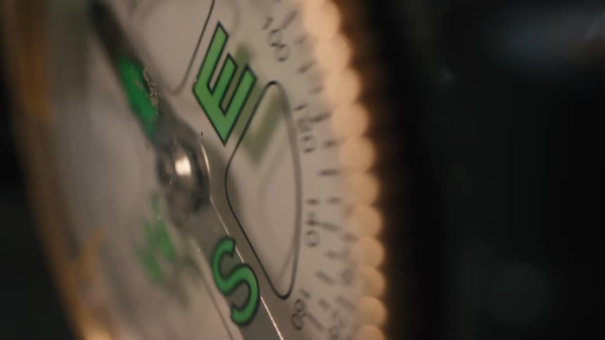A macro close-up captures a spinning compass needle erratically searching for a direction