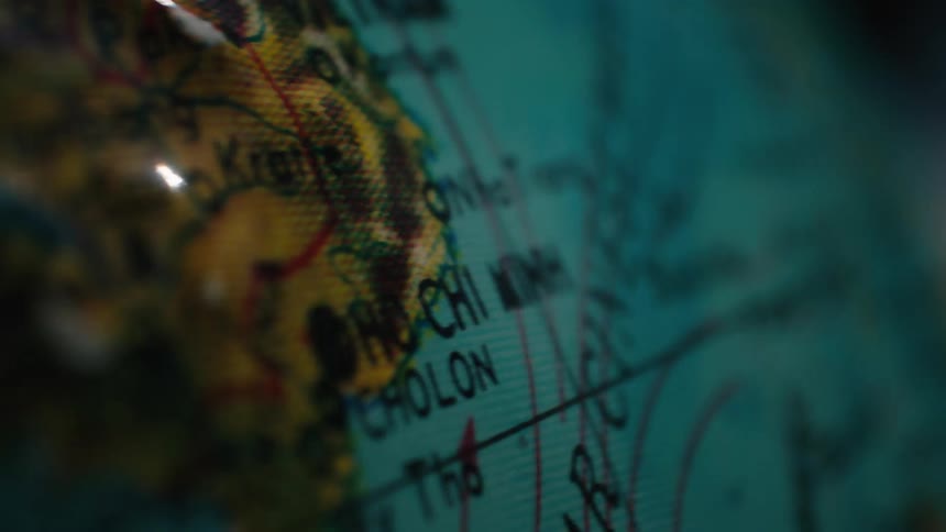A dimly lit, close-up view of a globe slowly panning over Southeast Asia