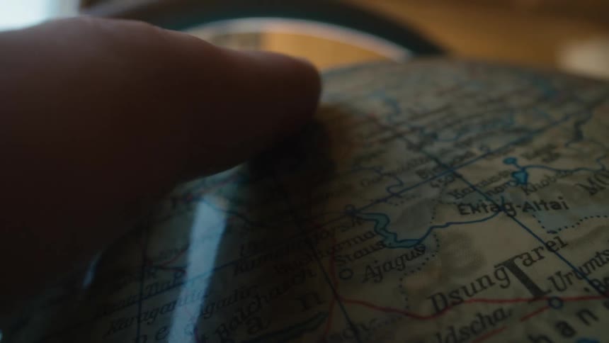 A close-up shot of a hand spinning a vintage globe, blurring across the map of Asia before stopping on a new destination