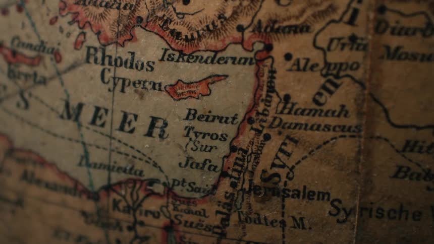 A static close-up shot focuses on a vintage, weathered globe map of the Middle East and Mediterranean Sea
