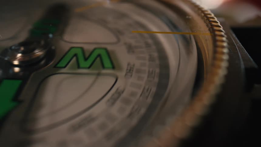 A close-up macro shot of a spinning compass dial slowing down and finding its direction