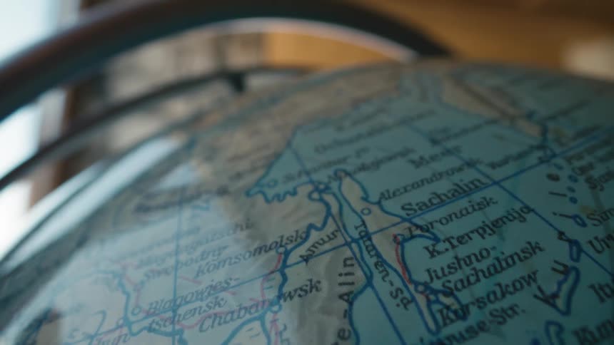 A hand gently spins a vintage globe, tracing a path across the countries of the world while planning a journey