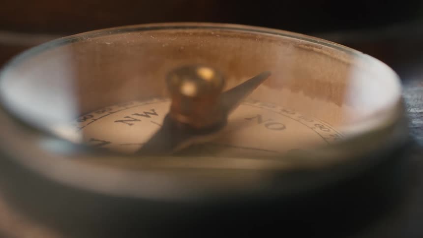 A macro shot of a vintage compass needle spinning erratically, symbolizing a search for direction