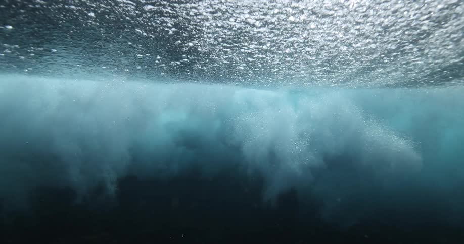 An incredible underwater slow-motion view of a powerful ocean wave crashing from below