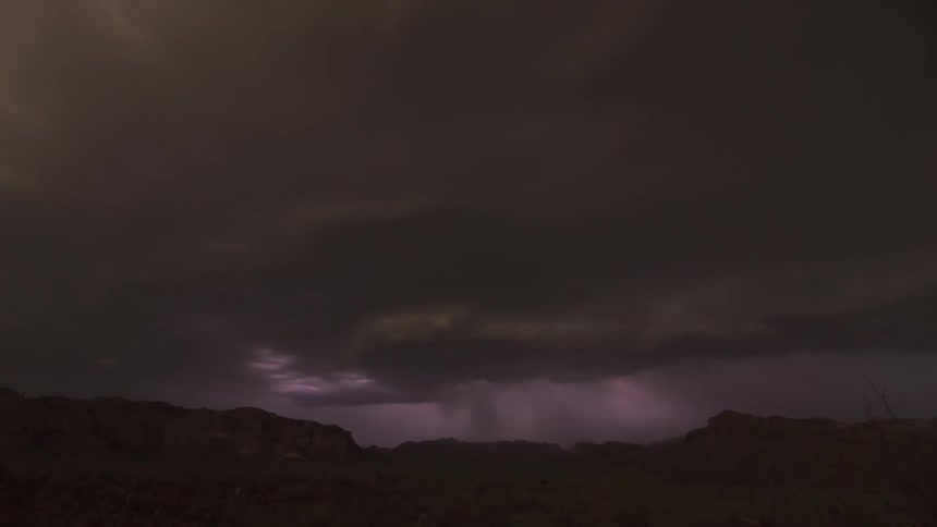 A powerful time-lapse of a thunderstorm unleashing a barrage of lightning within dark, swirling clouds over a silhouetted landscape at night