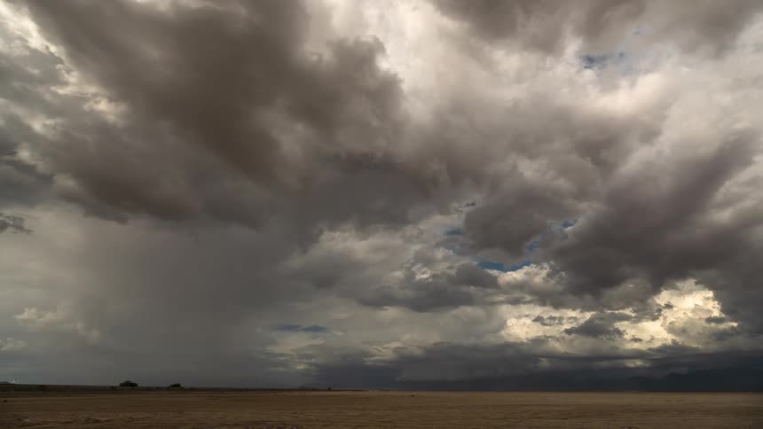 Ominous storm clouds gather and move across the sky above an empty desert plain