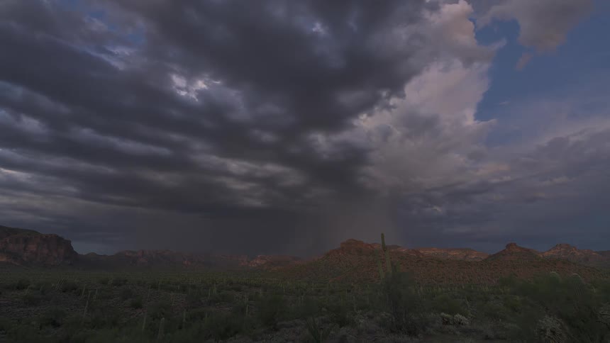 A dramatic time-lapse captures a powerful thunderstorm with multiple lightning strikes over a vast desert mountain landscape