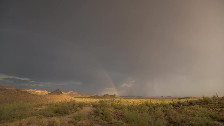 A dramatic timelapse shows a powerful rainstorm and a vibrant rainbow appearing over the Arizona desert landscape