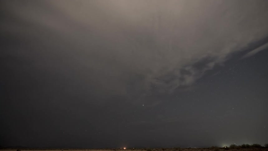 A time-lapse captures a massive storm cloud system moving across the sky at dusk, eventually clearing to reveal the brilliant stars of the night