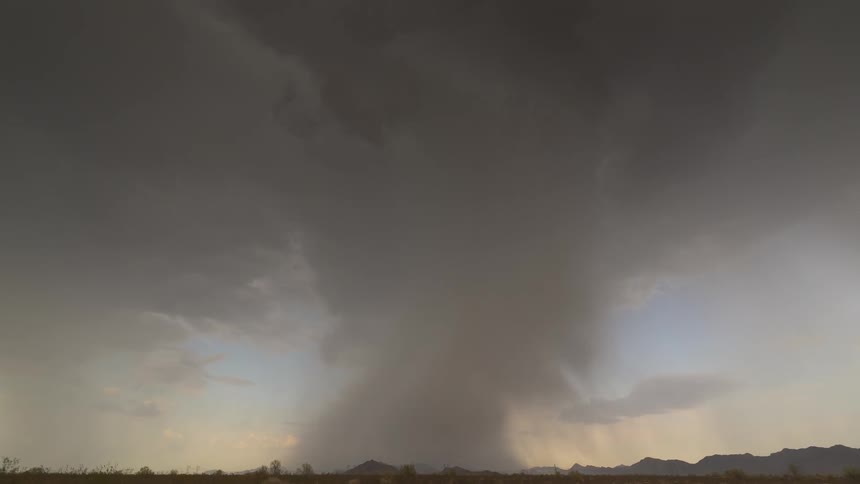 A dramatic time-lapse shows a severe thunderstorm and microburst unleashing heavy rain over a vast desert landscape