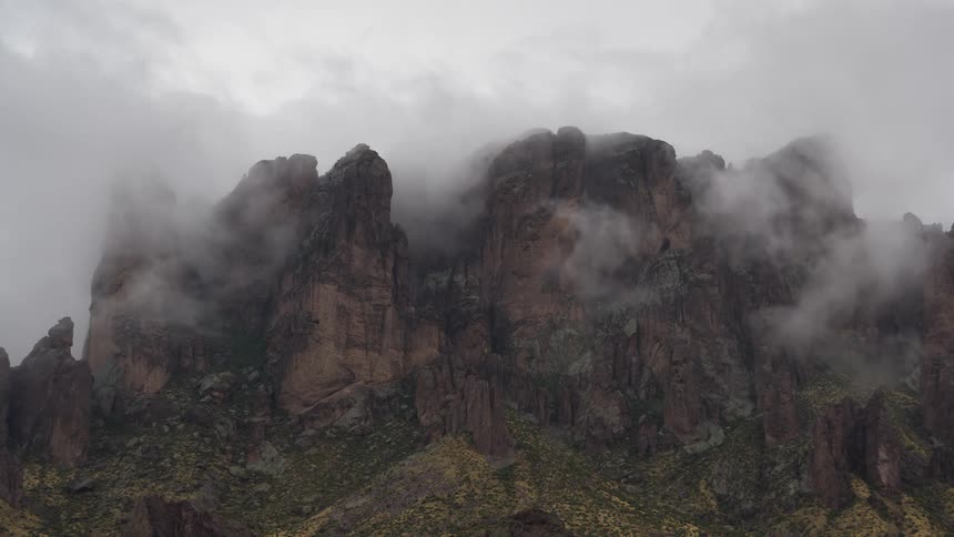 Timelapse of misty clouds swirling around the rugged peaks of the Superstition Mountains on an overcast day