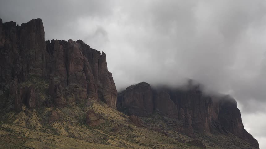 A dramatic time-lapse of stormy clouds and fog rolling over the peaks of a rugged mountain range