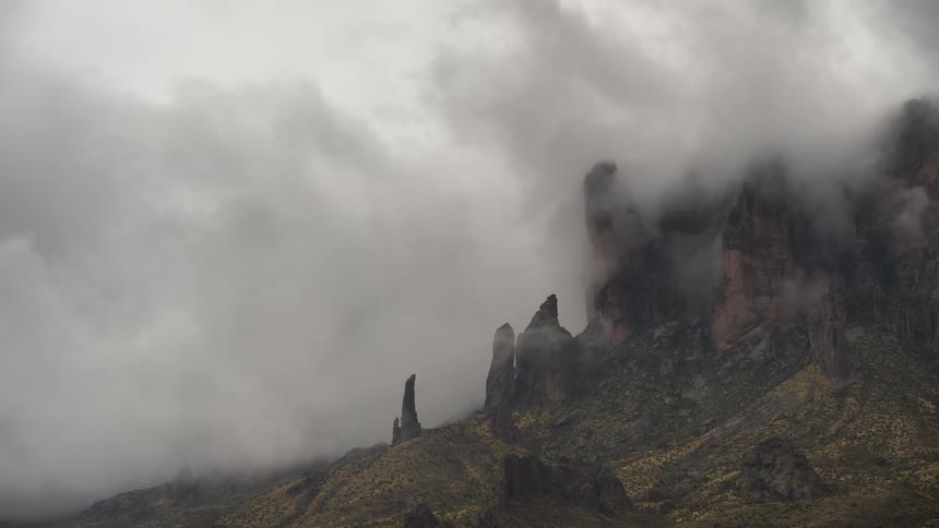 Mysterious fog and storm clouds envelop the jagged peaks of a majestic mountain range
