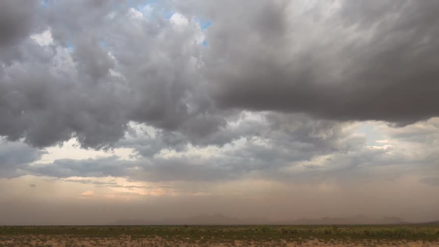 A powerful haboob dust storm moves across a flat desert landscape under dark, dramatic clouds