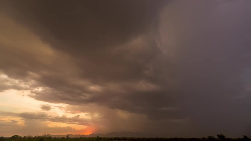 The sun sets on the horizon as a massive, dark storm front moves in, eventually engulfing the sky in a dramatic time-lapse