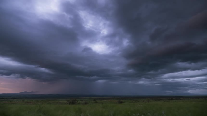 A powerful thunderstorm unleashes rain and spectacular lightning strikes across a vast landscape in a dramatic timelapse