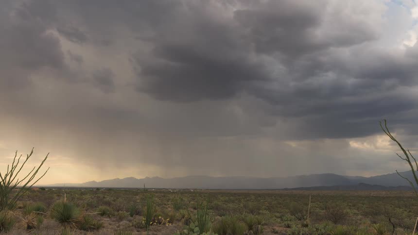 A dramatic time-lapse of a powerful monsoon rainstorm sweeping across the desert at dusk under dark, moody clouds