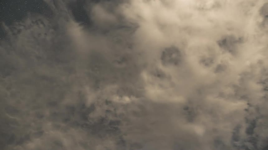 Mesmerizing timelapse of warm-toned clouds drifting across the starry night sky