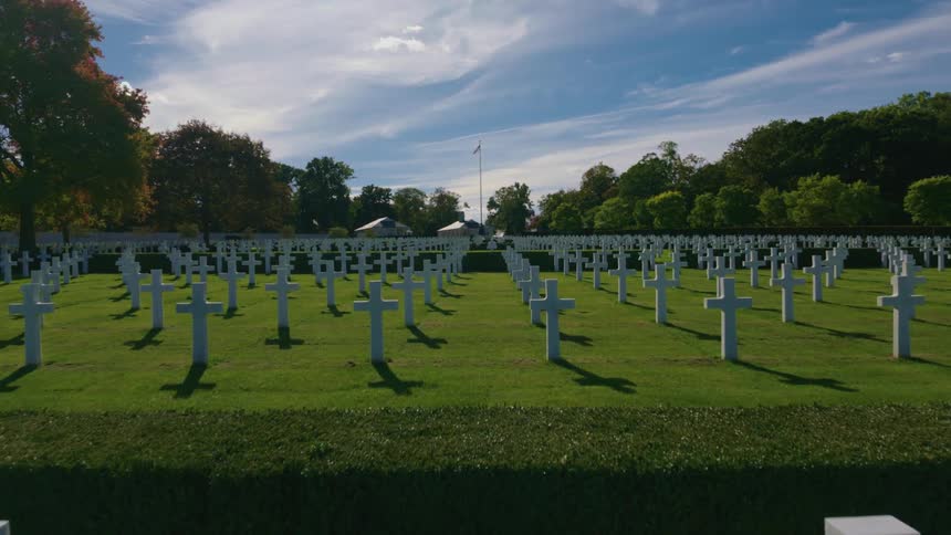 A slow crane shot reveals the endless rows of white crosses at the Normandy American Cemetery on a peaceful day