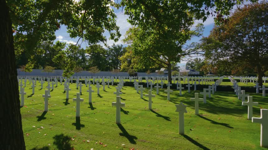 A slow pan across the sun-drenched graves at a military cemetery on a peaceful autumn day