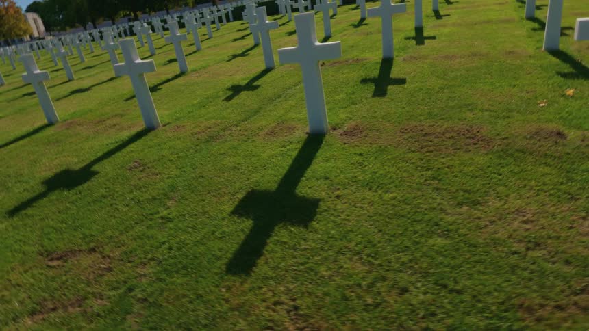 Slowly moving through the solemn rows of white crosses at a sunlit military cemetery