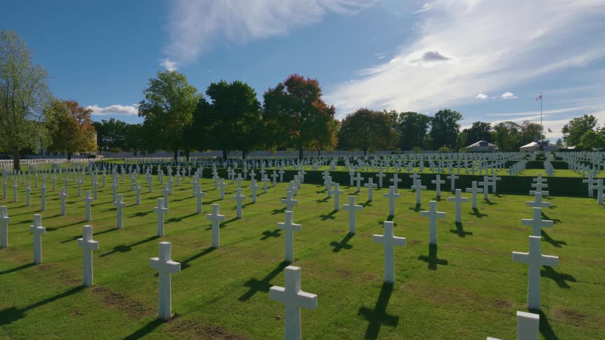 A serene time-lapse of the white cross headstones at a military cemetery on a sunny day with clouds passing overhead