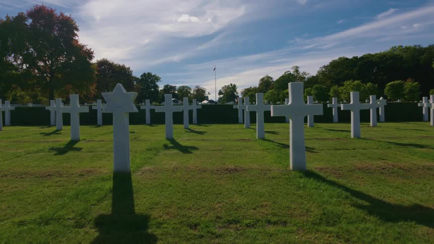 A solemn slow pan across the white gravestones of crosses and a Star of David at the Normandy American Cemetery and Memorial