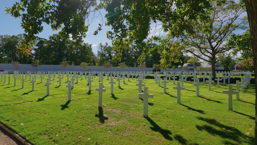 Sunlight casts long shadows from the rows of white marble crosses at the Normandy American Cemetery in France