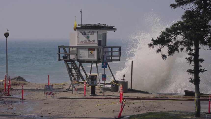 Powerful waves crash in slow motion behind a lifeguard tower on a closed section of Aliso Beach in Laguna Beach