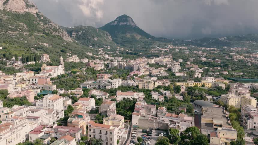 Aerial drone footage flying over the charming town of Sorrento, Italy, nestled in the mountains under a cloudy sky