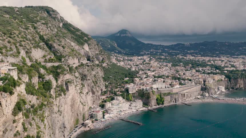 A stunning aerial view of the picturesque Italian coastal town of Sorrento, nestled into dramatic cliffs with Mount Vesuvius in the background