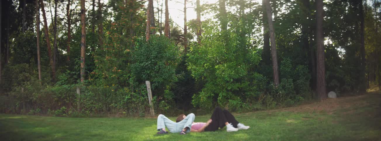 Two young women lie on their backs in a grassy field, enjoying a serene afternoon conversation amidst nature