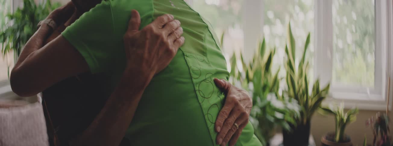 An elderly Asian couple finds comfort and solace in each other's arms with a long, emotional hug