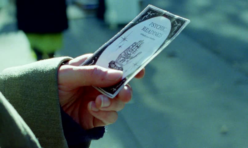 A mysterious business card advertising psychic readings is passed from one hand to another on a city street