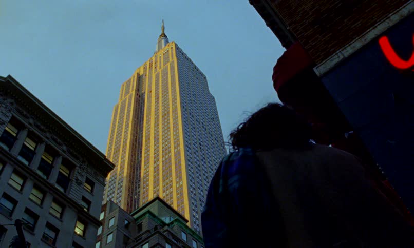 A low-angle shot captures the Empire State Building glowing in the sunset light in New York City