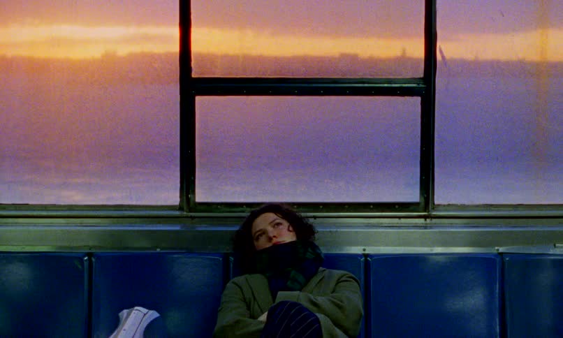 A thoughtful woman bundled in a scarf rests on a ferry or train during a vibrant purple and orange sunset