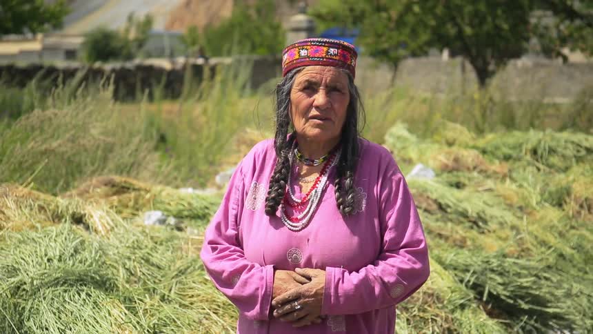 A woman stands in a grassy area on a sunny day