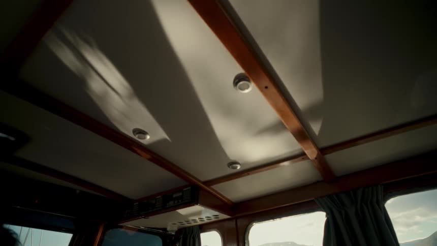 Sunlight streams into a classic wooden boat cabin, with the camera slowly tilting up to reveal moving shadows on the ceiling