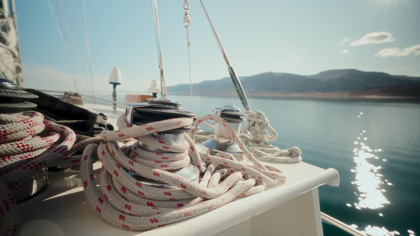 Close up shot of a sailing yacht's winch and coiled rope as it sails on a calm lake on a beautiful sunny day