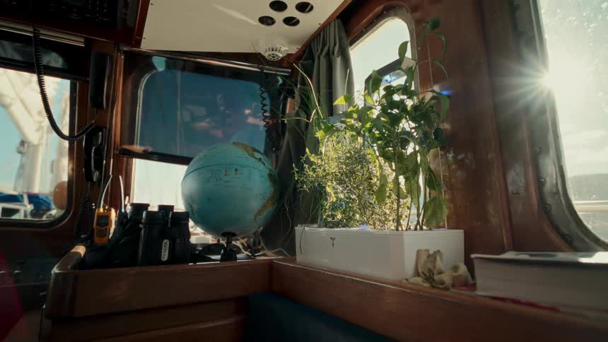 Cozy boat cabin interior with a globe and a small herb garden basking in the warm sunlight while sailing