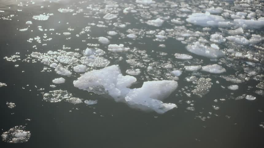 A close-up view of melting ice chunks and slush floating serenely on the water's surface