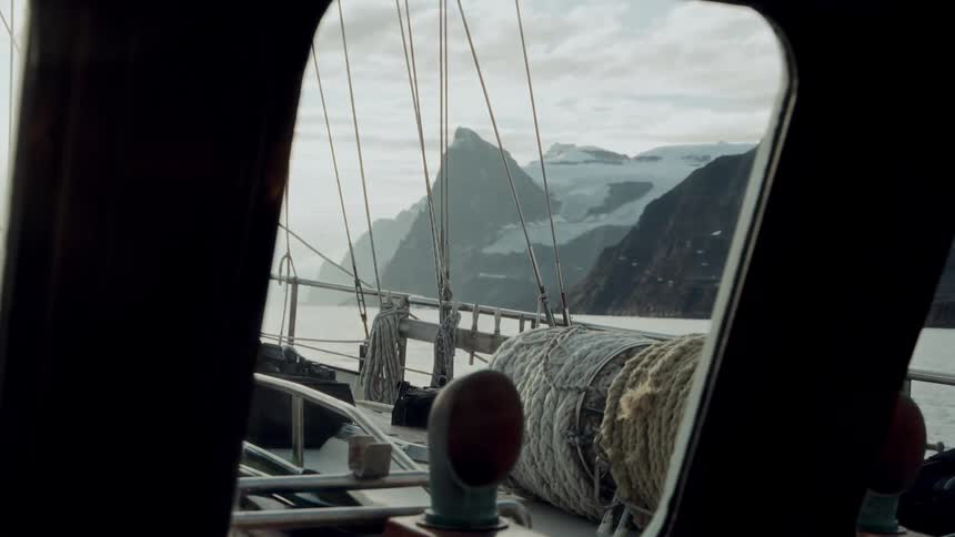 A scenic view of a majestic glacial mountain range from a boat sailing through a tranquil fjord