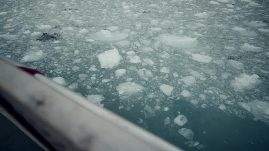 A slow reveal from a boat's railing captures the serene but cold landscape of a sea filled with chunks of floating ice