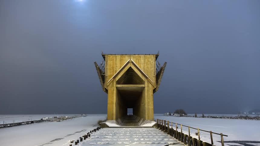 A stunning timelapse shows the moon and clouds passing over a striking wooden building in a vast, snow-covered winter landscape from night to dawn
