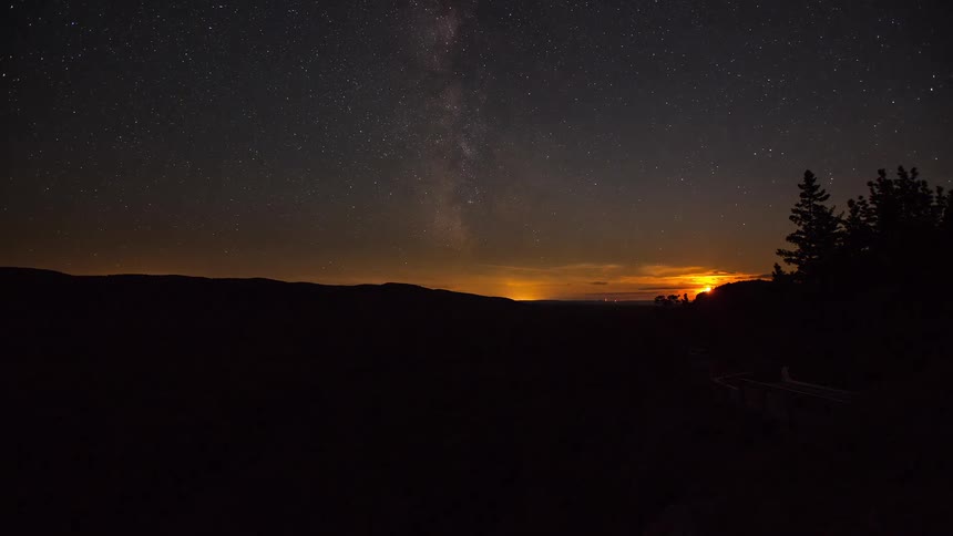 A beautiful timelapse of the moon setting over a forested mountain valley, revealing the majestic Milky Way galaxy in the starry night sky