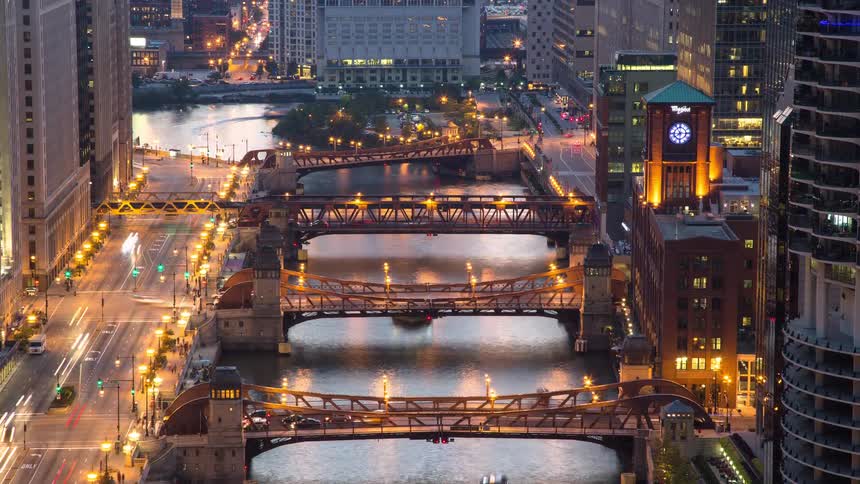 High angle timelapse of the Chicago River and its iconic drawbridges, showing bustling car and boat traffic from dusk until nightfall