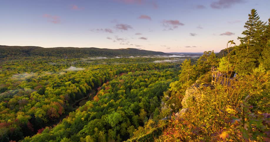 A stunning sunrise timelapse over a misty mountain valley, showcasing a vibrant autumn forest from a scenic lookout point
