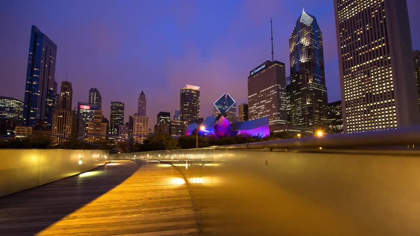 A dynamic night timelapse from the BP Pedestrian Bridge in Chicago's Millennium Park reveals the illuminated skyline and busy traffic below